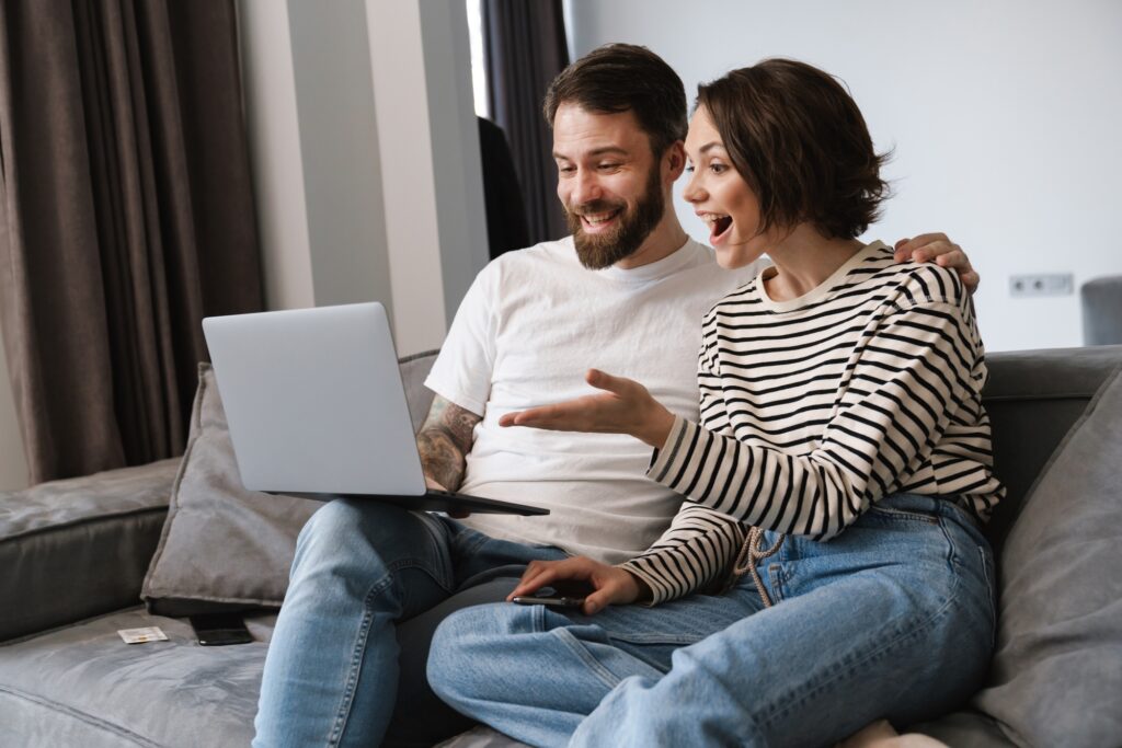 Happy young white couple looking at laptop computer